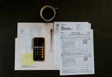 black Android smartphone near ballpoint pen, tax withholding certificate on top of white folder