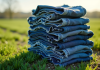 Pile de jeans usés dans un champ vert ensoleille
